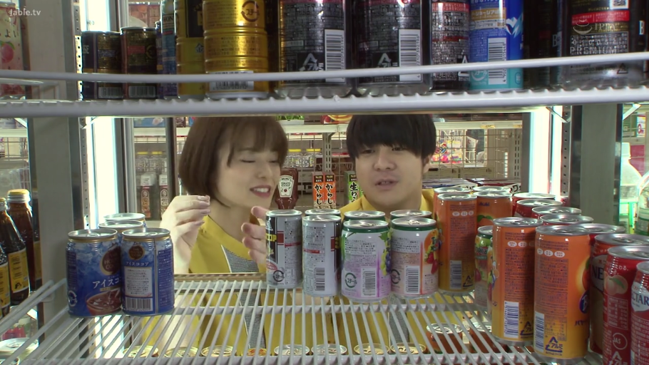 交谈 · 站立 · 中景 · 微笑 · 便利店 · 罐装饮料 · 黄色制服 · 货架视角