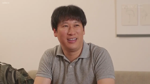 坐姿 · 微笑 · 面部特写 · 谈话 · 室内房间 · 双肩包 · 男性角色 · 灰色翻领POLO衫