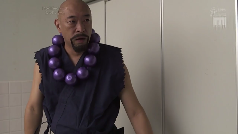 室內 · 站立 · 上半身特寫 · 侧头注视 · 深蓝色无袖僧袍 · 严肃惊讶 · 紫色大念珠 · 秃头胡须男