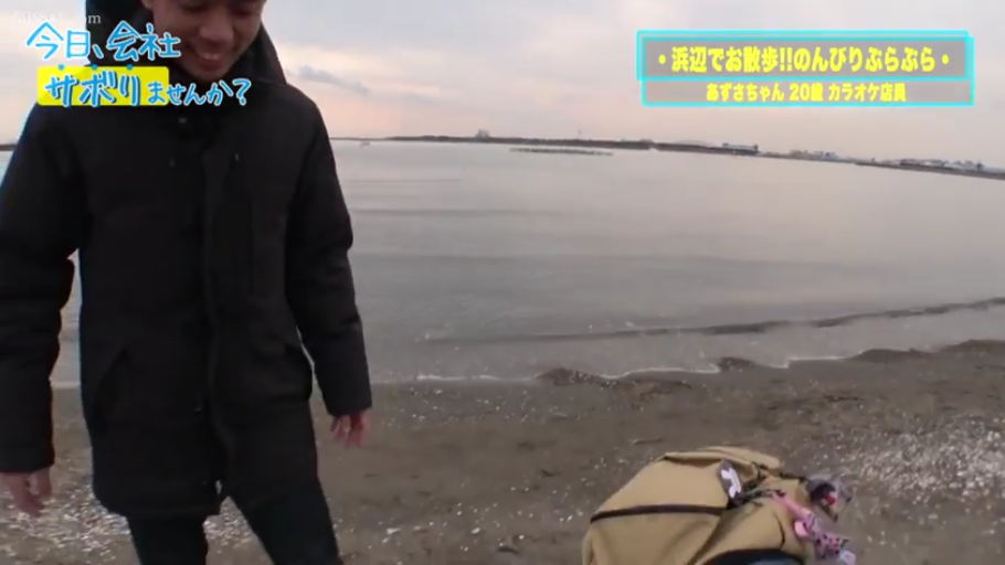 站立 · 中景 · 微笑 · 户外 · 背包 · 海滩 · 闲逛 · 黑色羽绒服