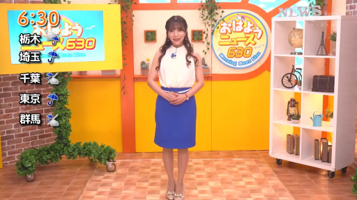 站立 · 微笑 · 演播室 · 新闻播报 · 电视截图 · 白衣蓝裙职业装 · 布景道具