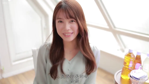 坐姿 · 面对镜头 · 半身特写 · 甜美微笑 · 棕色长发 · 明亮室内 · 瓶装饮料 · 浅绿色V领上衣