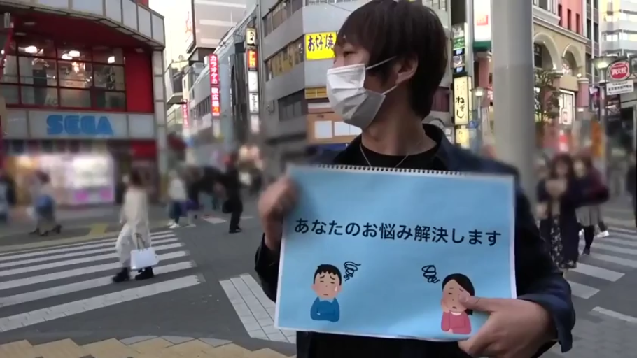 站立 · 中景 · 平静 · 黑色夹克 · 路人 · 城市街道 · 展示告示牌 · 蓝色告示牌