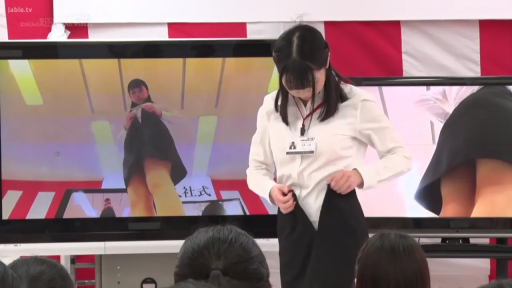 站立姿势 · 专注表情 · 演播厅 · 中景画面 · 白衬衫黑裙制服 · 掀起短裙 · 显示屏幕 · 露出白色内裤