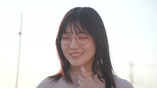 面部 · 眼镜 · 站立 · 侧身 · 微笑 · 户外 · 长发 · 粉色针织衫