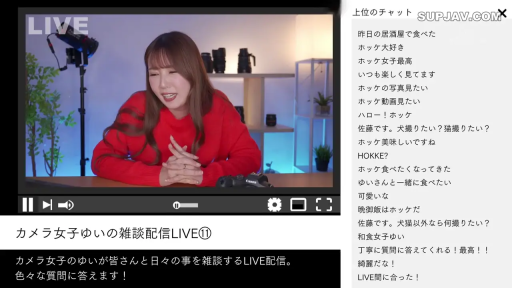 坐姿 · 微笑 · 半身 · 室内摄影棚 · 直播互动 · 相机镜头 · 红色长袖毛衣 · 视频播放器界面