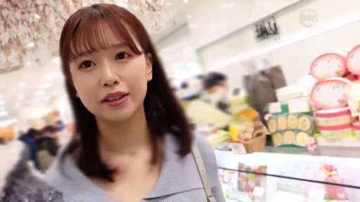 站立 · 微笑 · 注视镜头 · 齐刘海长发 · 单肩包带 · 商场内部 · 浅蓝色针织上衣 · 头部及肩膀特写