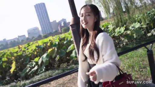 自然交谈 · 湖边 · 深色内搭 · 红色手提包 · 面部表情特写 · 背景有城市高楼
