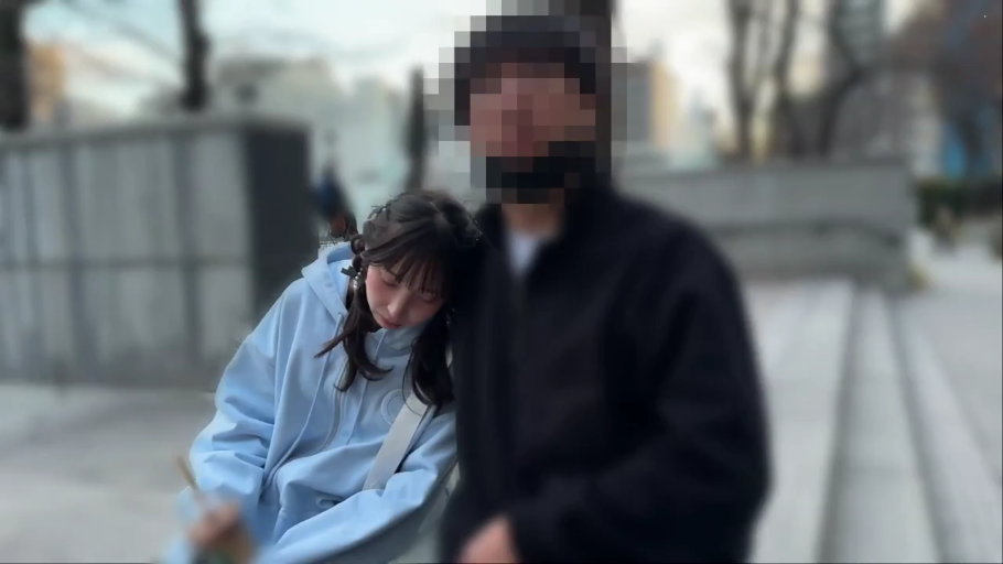 挎包 · 男方脸部打码 · 两人中景 · 蓝色连帽卫衣 · 公园小路 · 头部靠肩 · 散步依偎 · 平淡忧伤