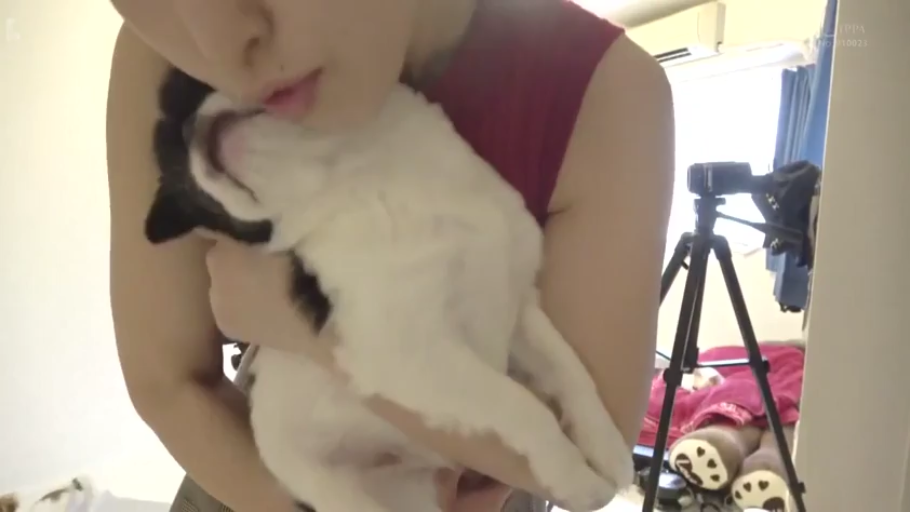上半身特写 · 室内房间 · 居家风格 · 自然表情 · 红色无袖背心 · 三脚架摄像机 · 站立抱狗 · 亲吻宠物